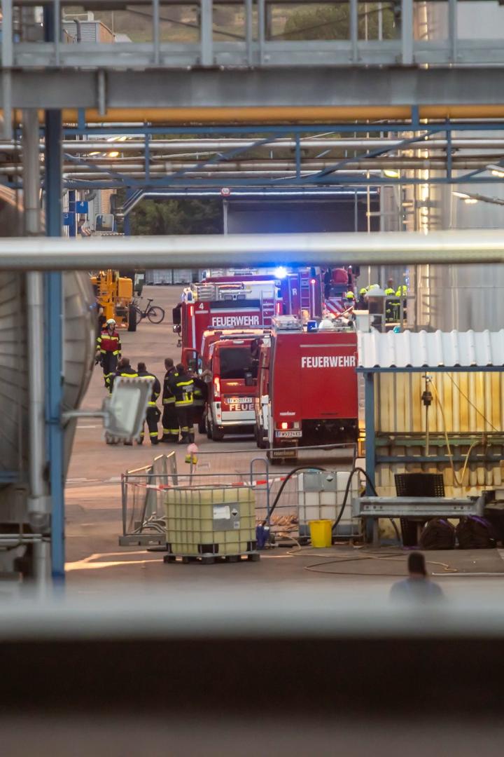 Feuerwehrleute und Einsatzfahrzeuge in einem Industriegelände.