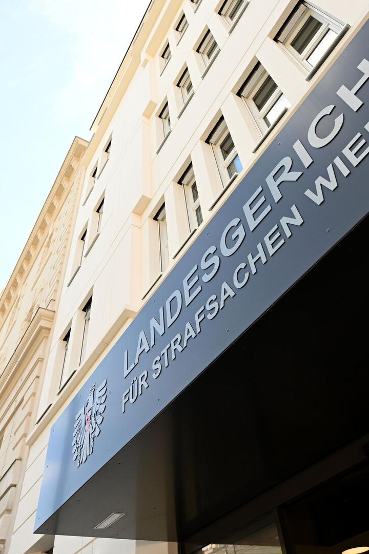Schräger Blick auf ein Wiener Landesgericht mit Straßenschild und Straßenlaterne.