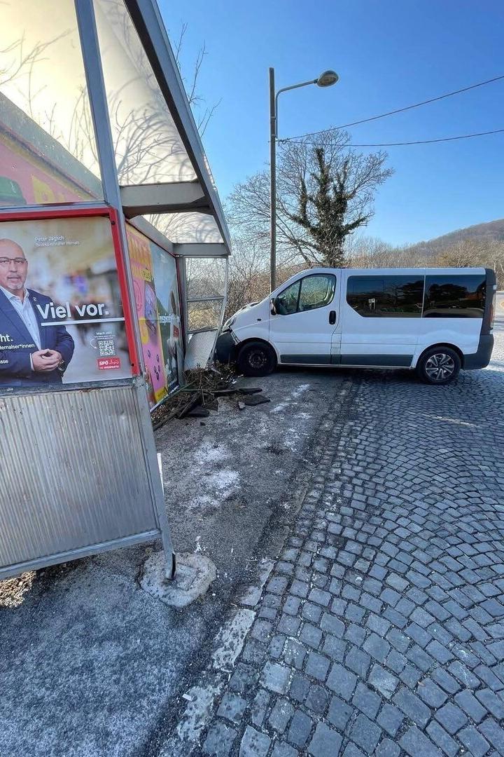 Weißer Lieferwagen prallt gegen eine Bushaltestelle, eine Werbetafel ist beschädigt.