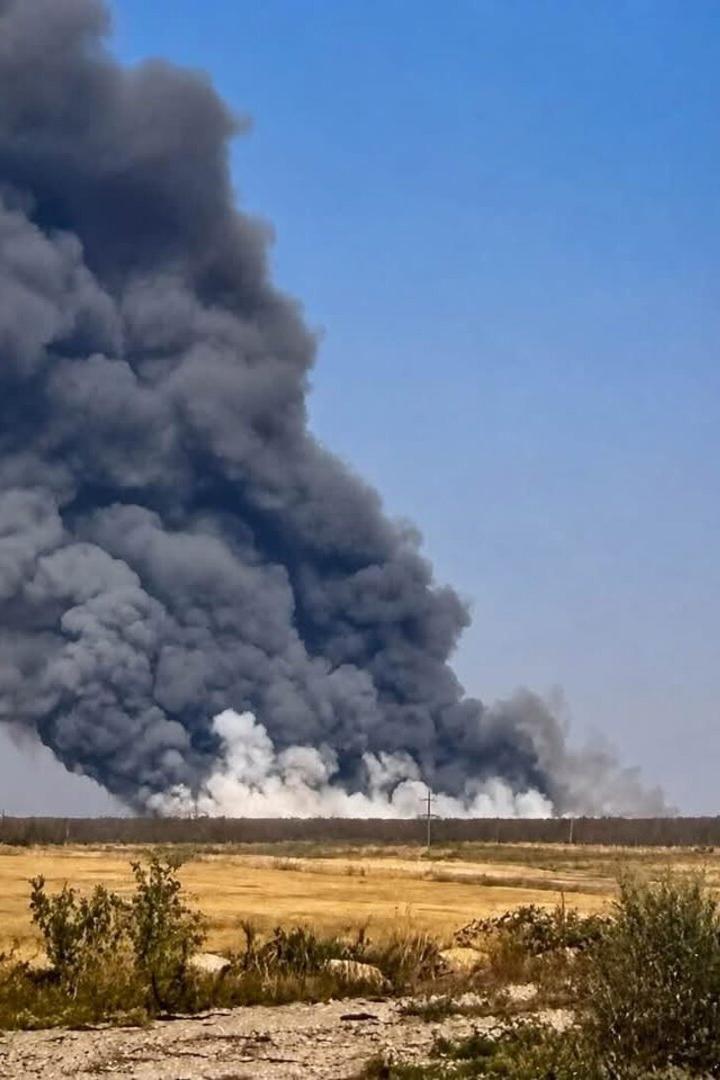 Dicker schwarzer Rauch steigt hinter einer trockenen Landschaft in den Himmel.