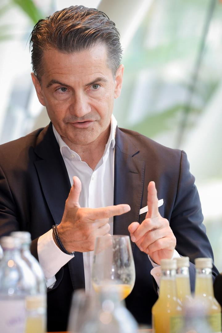 Ein Mann im Anzug spricht bei einem Tischgespräch und gestikuliert mit den Händen.