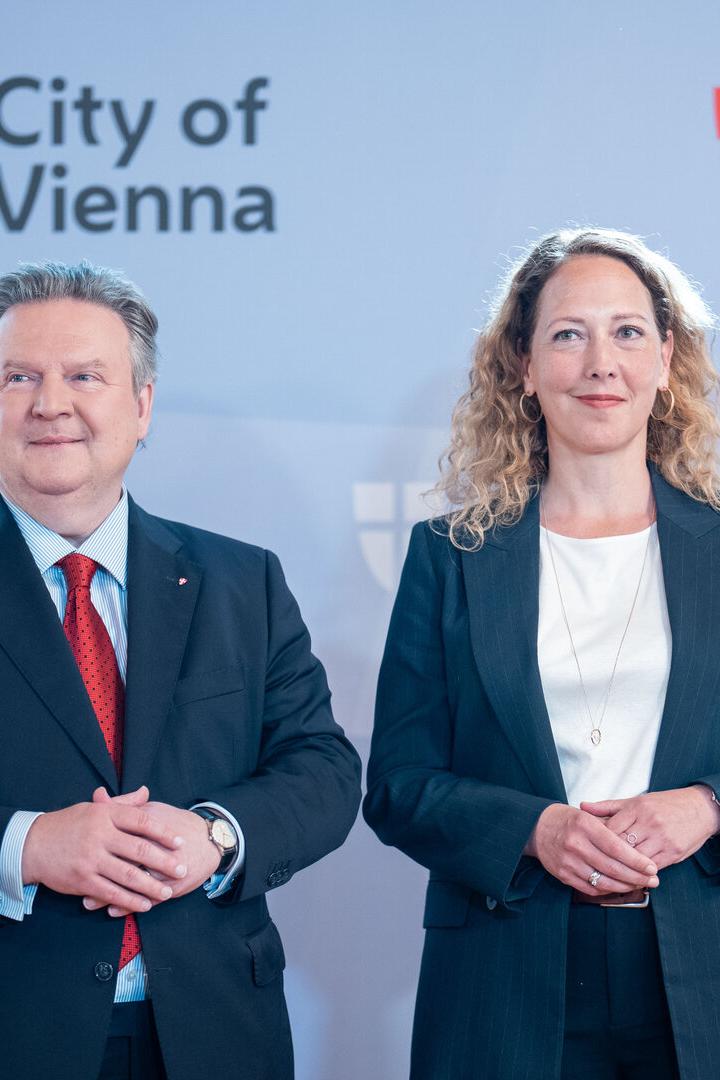 Michael Ludwig und Judith Pühringer stehen vor einer Wand mit dem Logo der Stadt Wien.