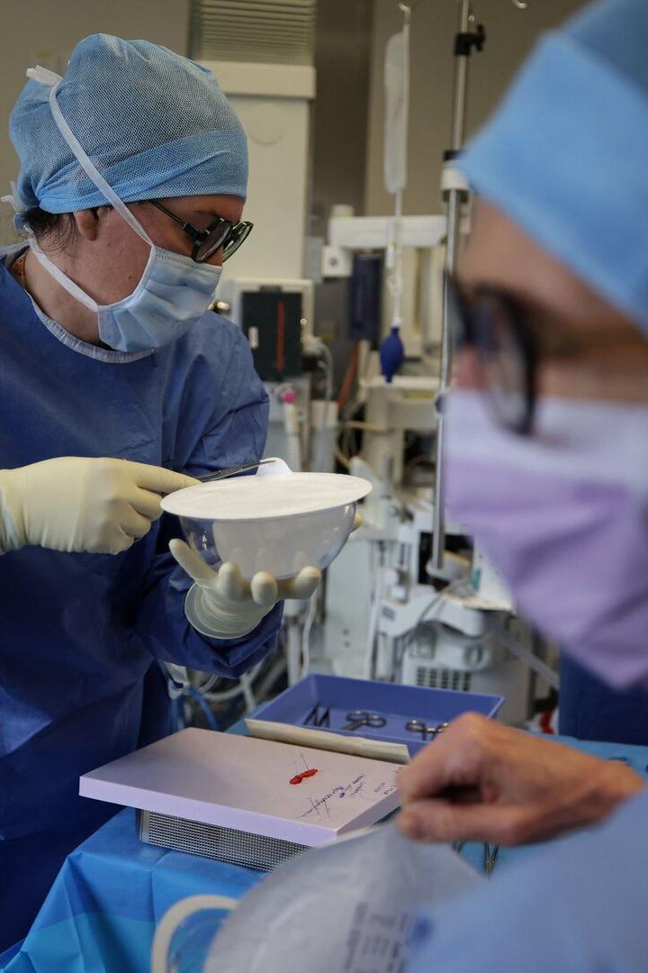 Zwei medizinische Fachkräfte in OP-Kleidung bereiten in einem Krankenhaus sterile Instrumente und Materialien für einen Eingriff vor.