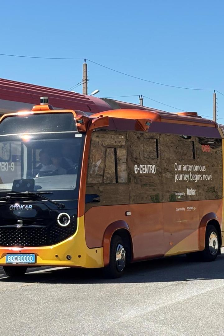 Neuer gelb-orangener ÖBB E-Postbus vor Zug