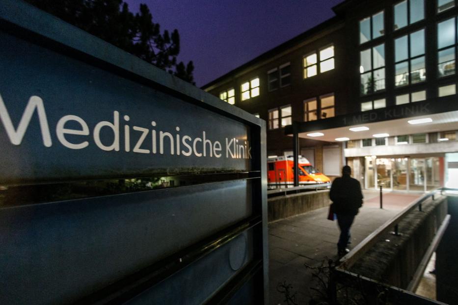 Ein Schild der Medizinischen Klinik mit einem Krankenwagen und einer Person im Hintergrund.