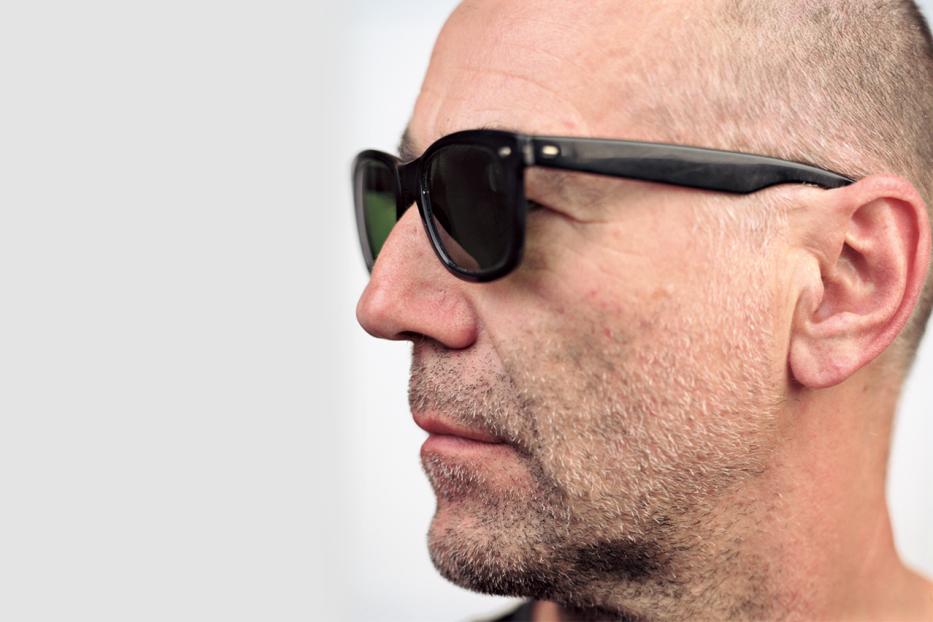 Ein Mann mit Sonnenbrille, von der Seite aufgenommen.