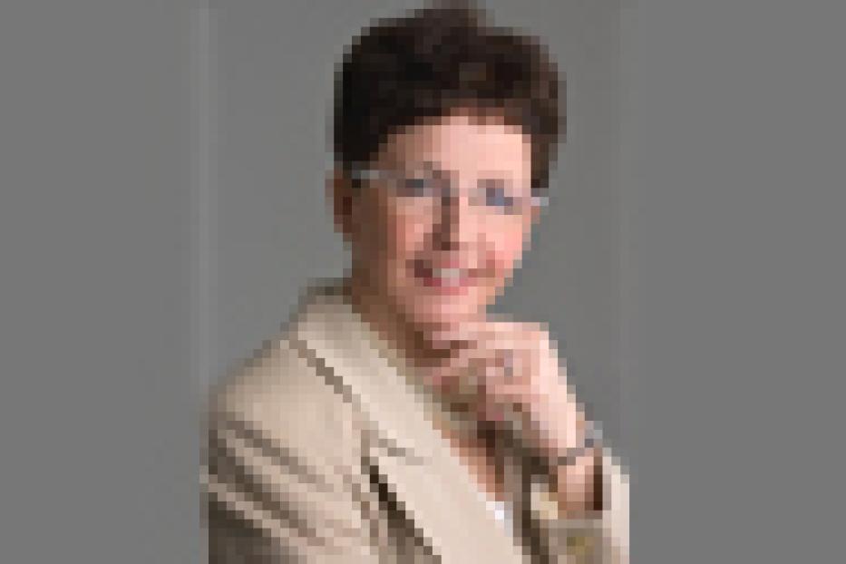 Eine Frau mit Brille und kurzem, dunklem Haar lächelt in die Kamera.