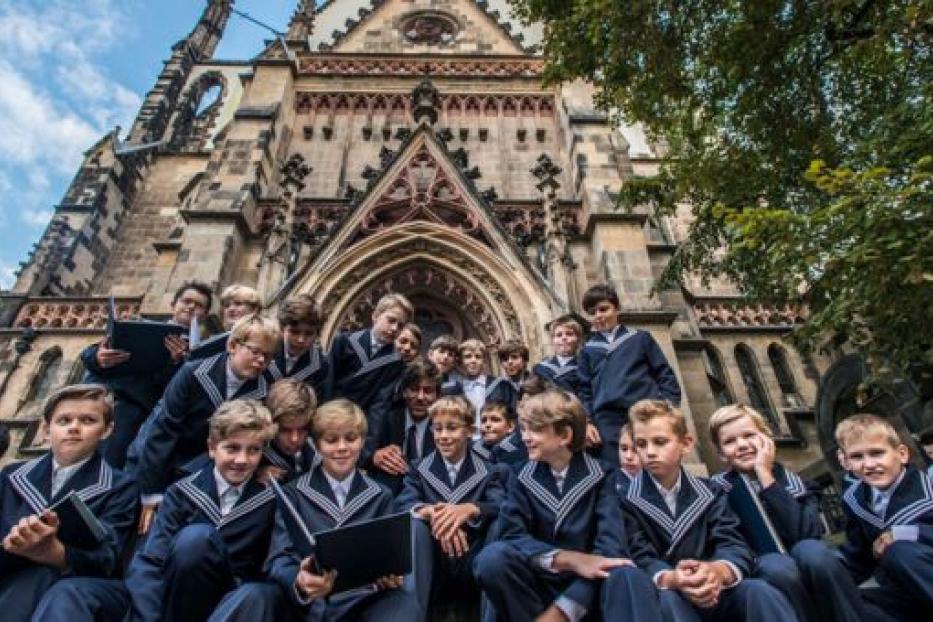Eine Gruppe von Jungen in Uniform sitzt vor einem großen Gebäude.