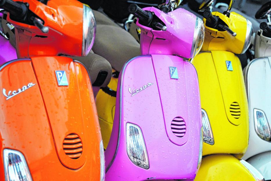 Mehrere farbenfrohe Vespa-Roller stehen nebeneinander.