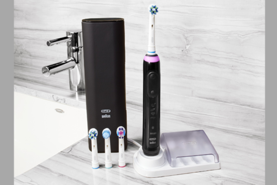 Eine elektrische Oral-B Zahnbürste mit Zubehör auf einem Waschtisch.