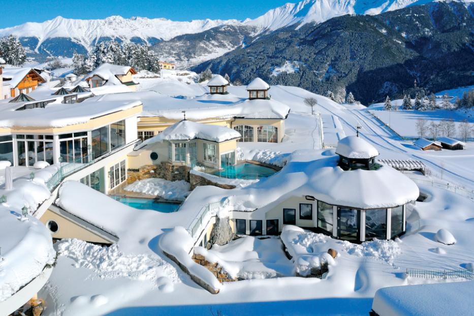 Ein verschneites Hotelresort in den Bergen mit Außenpools.