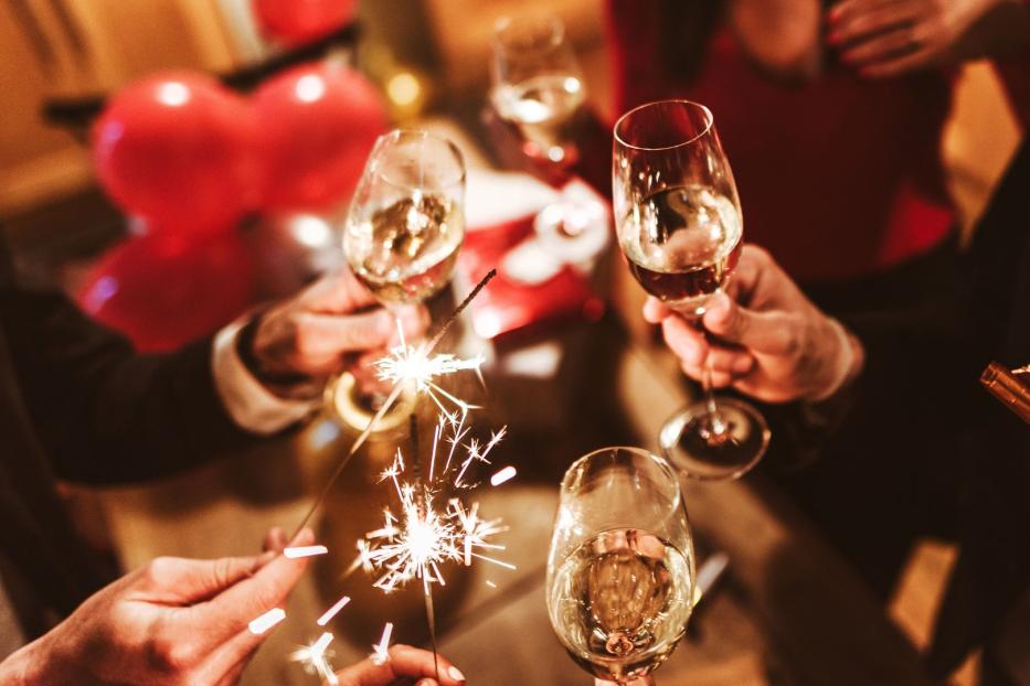 Menschen feiern Silvester mit Sekt und Wunderkerzen.