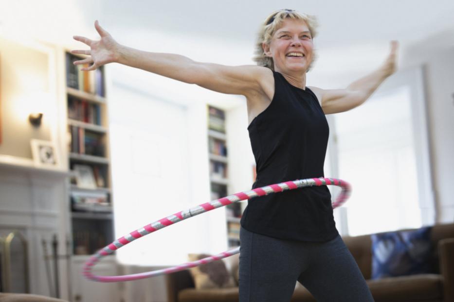Frau hat Spaß an Bewegung mit Hula Hoop-Reifen.