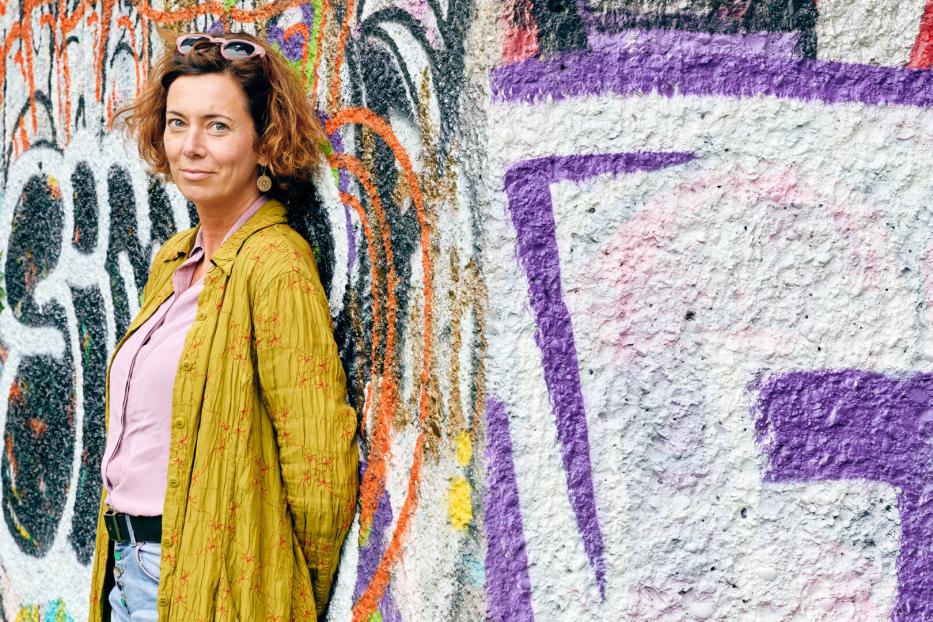 Eva Menasse steht vor einer mit Graffiti bemalten Wand.