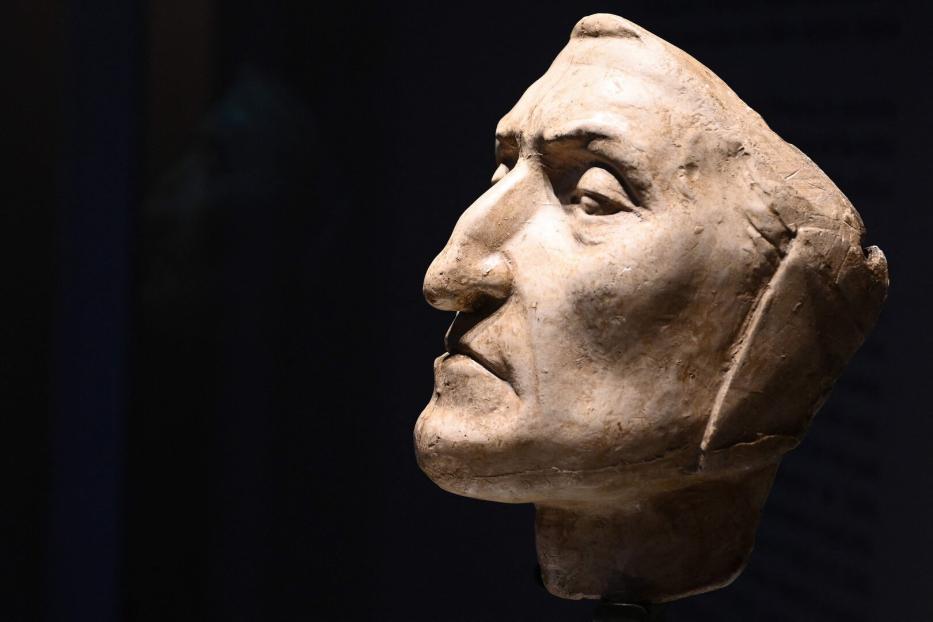 Nahaufnahme einer Skulptur eines Mannes vor einem dunklen Hintergrund.