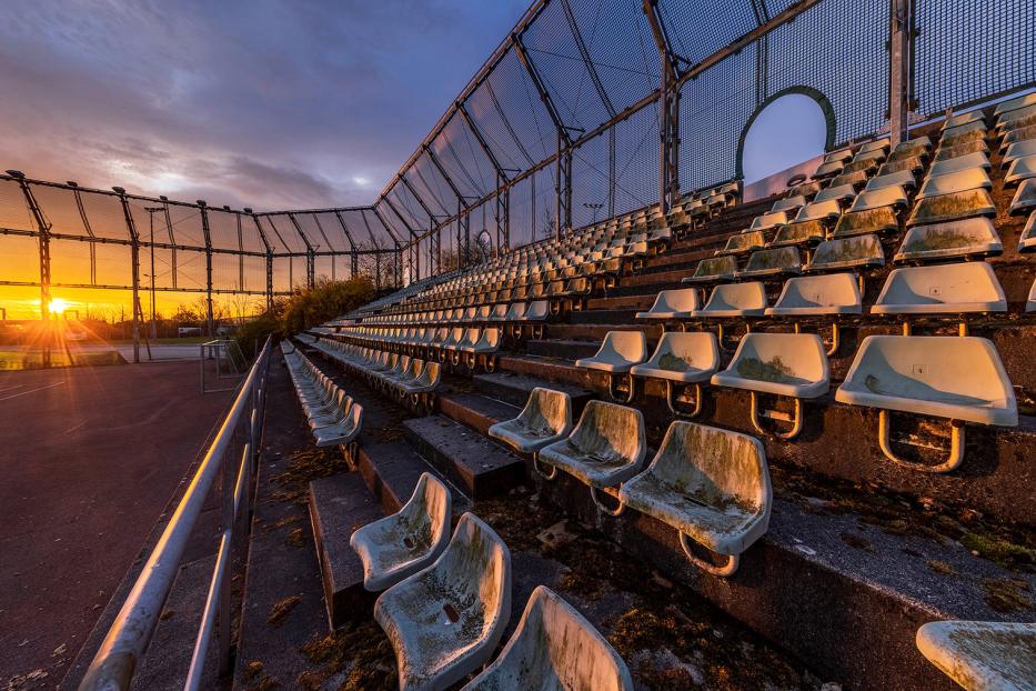 Verlassene Tribüne eines Sportplatzes bei Sonnenuntergang.