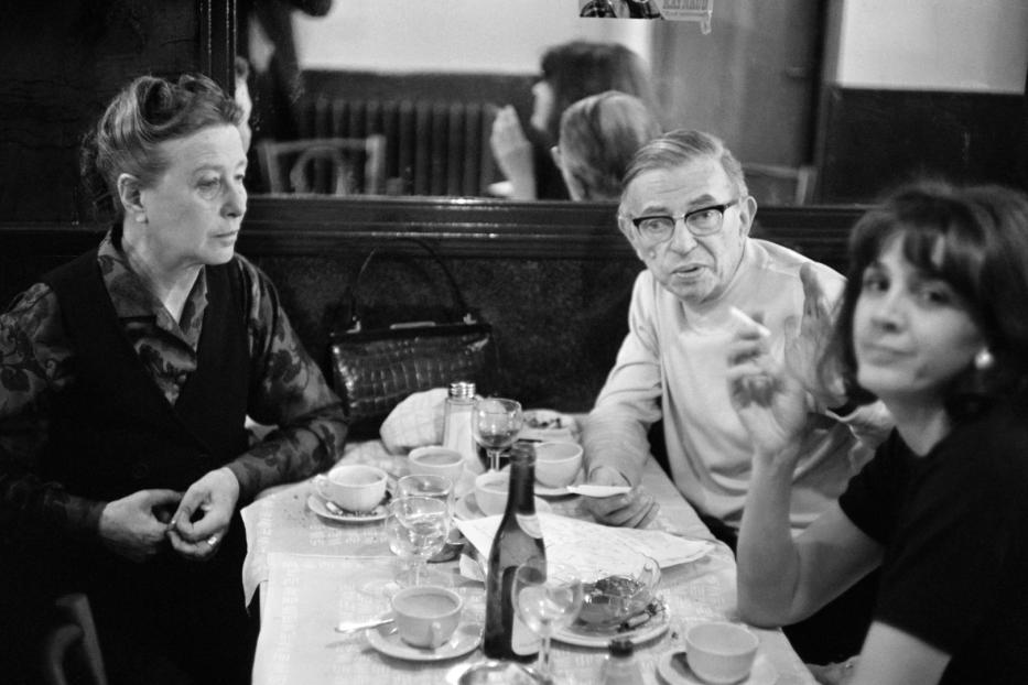 Drei Personen sitzen an einem Tisch in einem Café, vermutlich in Gespräch vertieft.