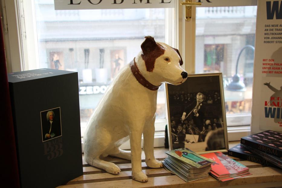 Eine Schaufensterdekoration mit einer Hundestatue, Büchern und einem gerahmten Foto.