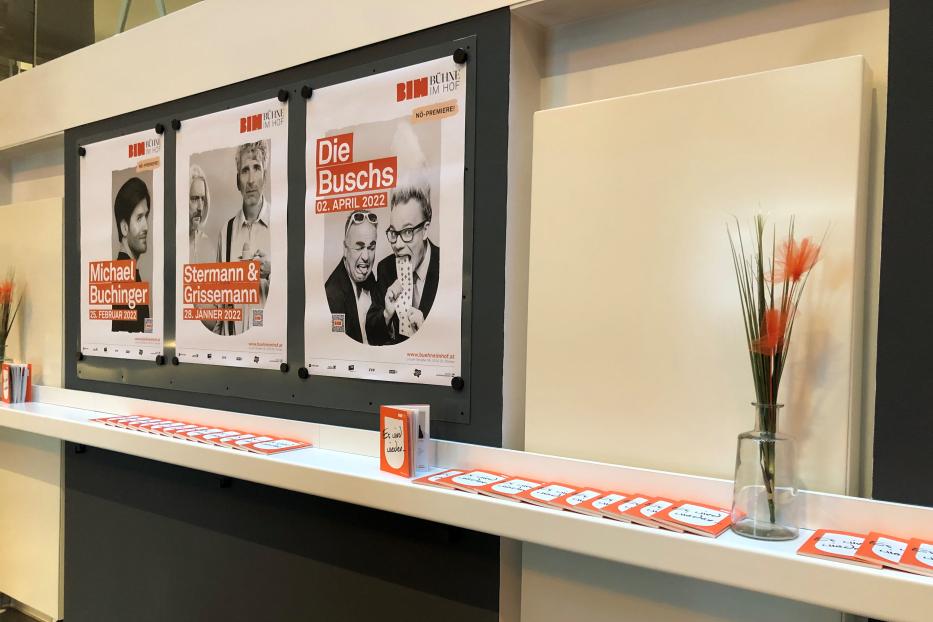 Drei Theaterplakate für Michael Buchinger, Stermann & Grissemann und „Die Buschs“ hängen an einer Wand.