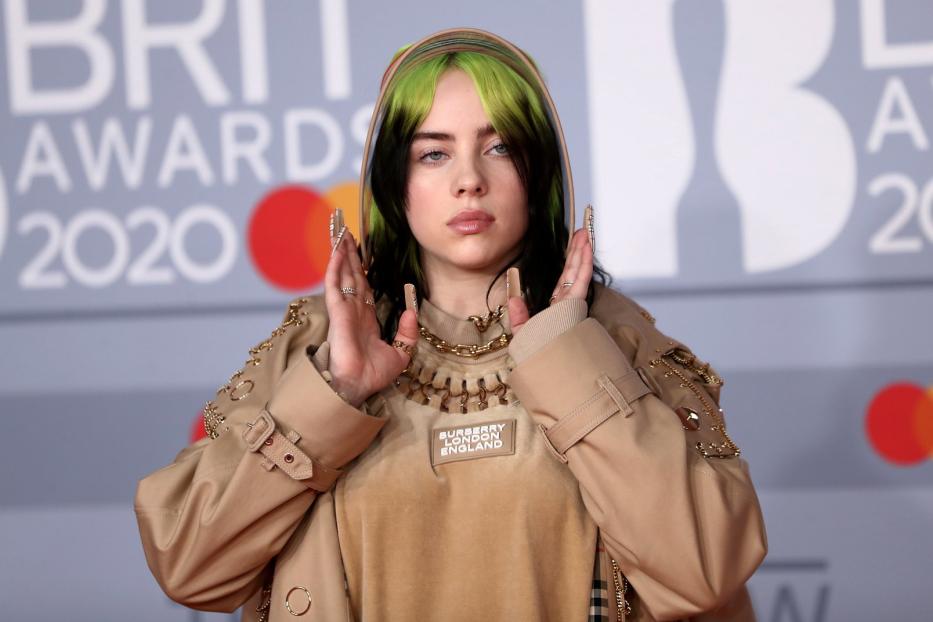 Billie Eilish bei den BRIT Awards 2020 mit grün-schwarzen Haaren und beiger Kleidung.