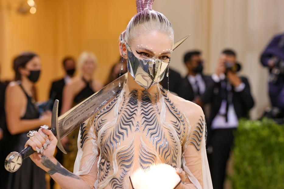 Grimes in einem futuristischen Outfit mit Schwert und Buch auf der Met Gala 2021.