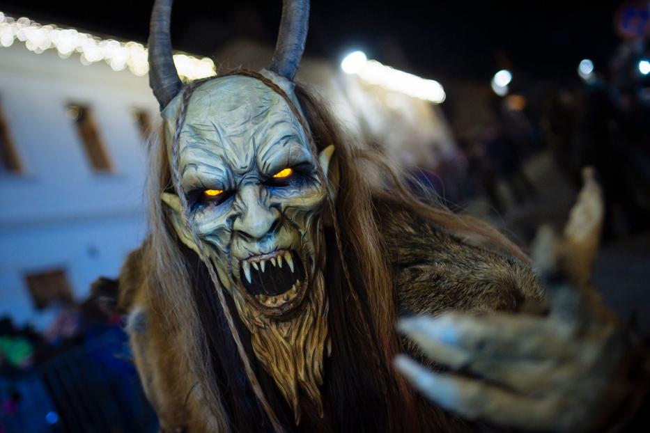 Ein Krampus mit Hörnern, Fell und einer furchteinflößenden Maske mit leuchtenden Augen.