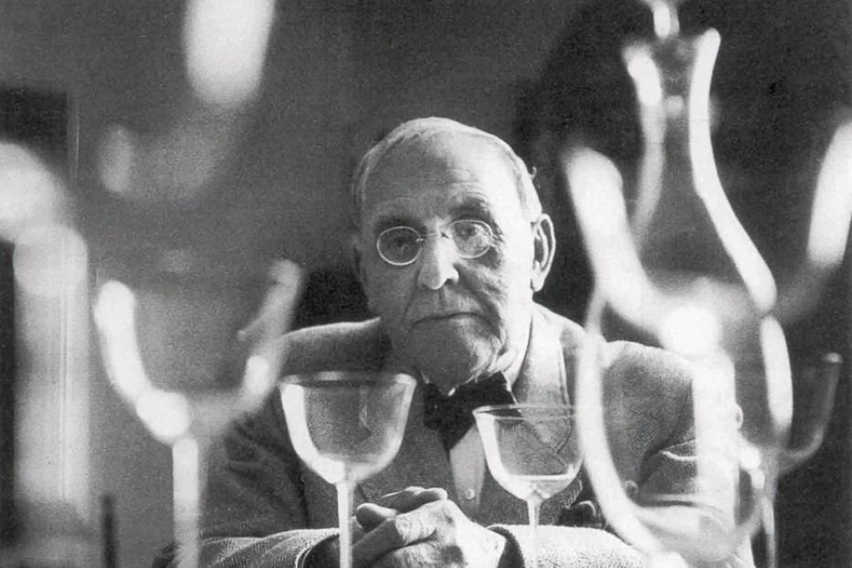 Der Fotograf Man Ray hinter einer Reihe von Gläsern und einer Karaffe.