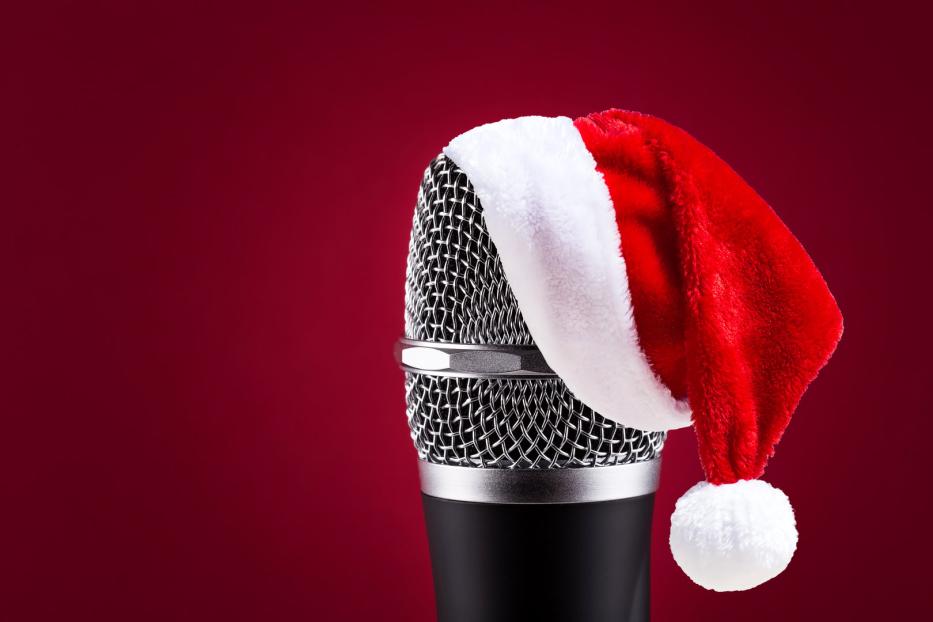 Ein Mikrofon trägt eine rote Weihnachtsmütze vor einem roten Hintergrund.