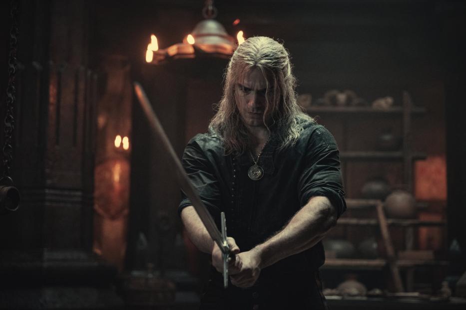 Geralt von Riva hält ein Schwert in den Händen.