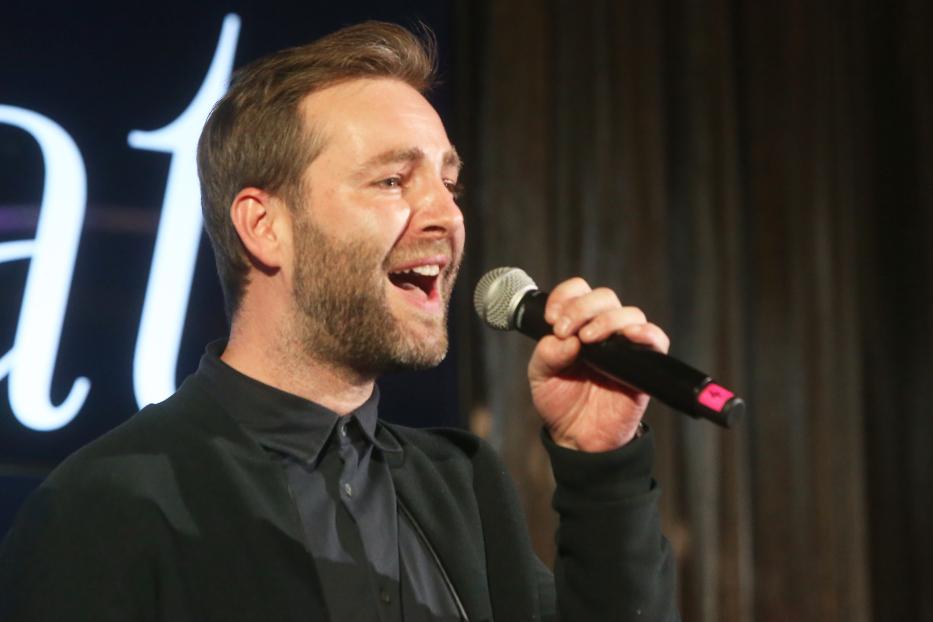 Josh hält ein Mikrofon und spricht.