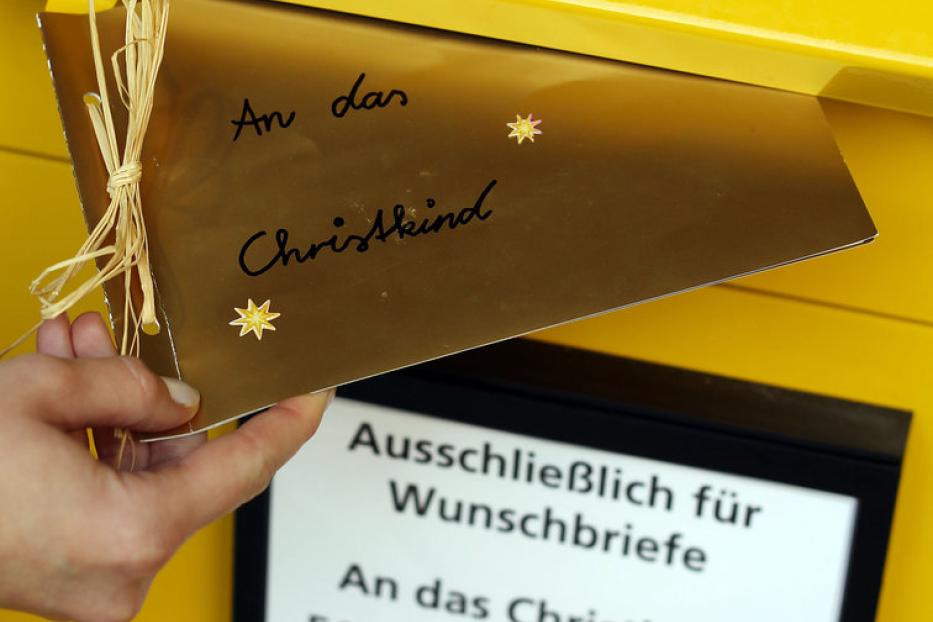Ein Brief „An das Christkind“ wird in einen gelben Briefkasten in Engelskirchen eingeworfen.