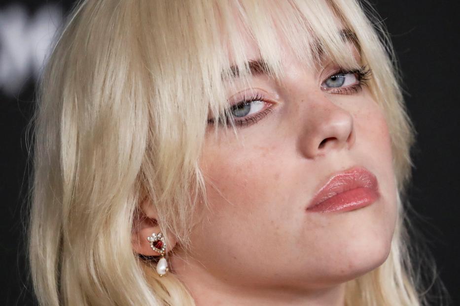 Nahaufnahme von Billie Eilish mit blonden Haaren und einem herzförmigen Ohrring.