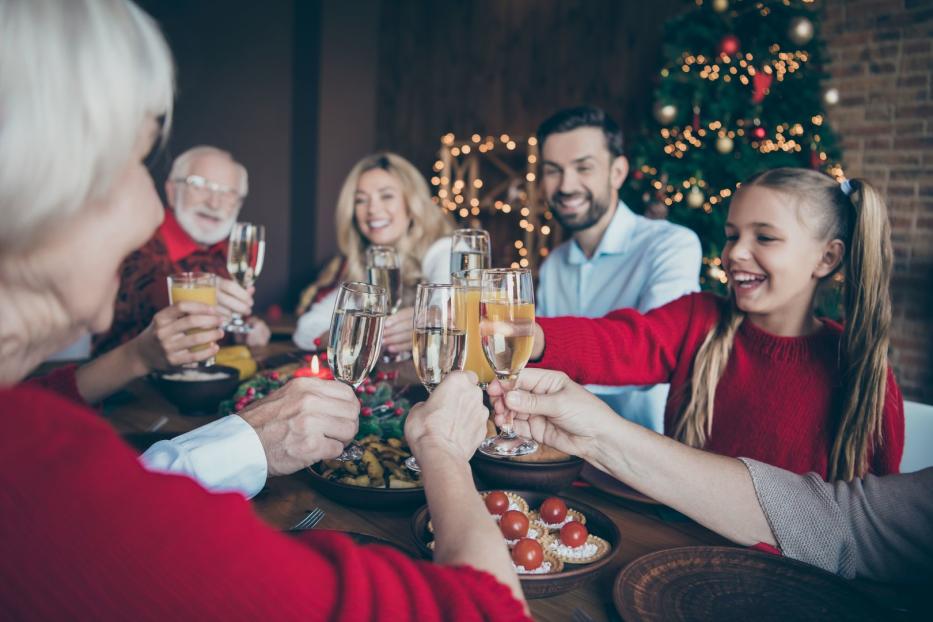 Eine Familie stößt an Weihnachten mit Sekt und Saft an einem festlichen Tisch an.