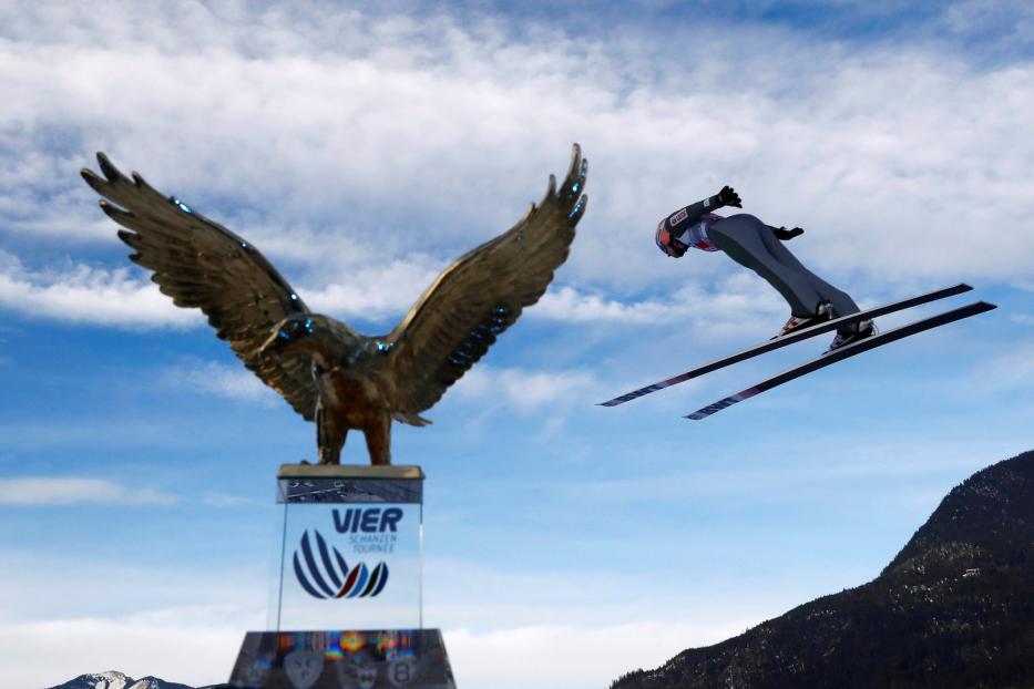 Ein Skispringer in der Luft vor dem Adler-Denkmal der Vierschanzentournee.