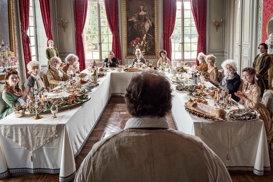 Eine festliche Tafelrunde mit Personen in historischer Kleidung in einem opulenten Saal.