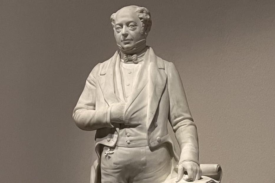 Eine Statue von Lord Brougham in Anzug und mit einer Schriftrolle in der Hand.