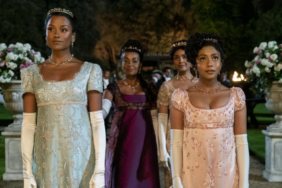 Frauen in Regency-Kleidern und Schmuck stehen bei einer formellen Veranstaltung.
