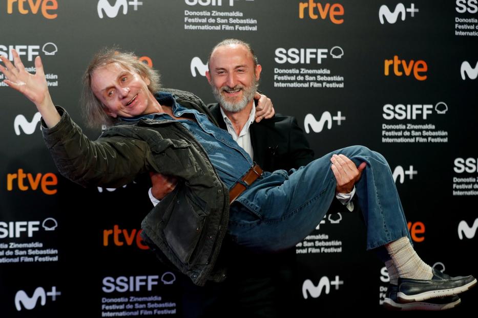 Ein Mann trägt einen anderen Mann auf dem roten Teppich des San Sebastián Film Festivals.