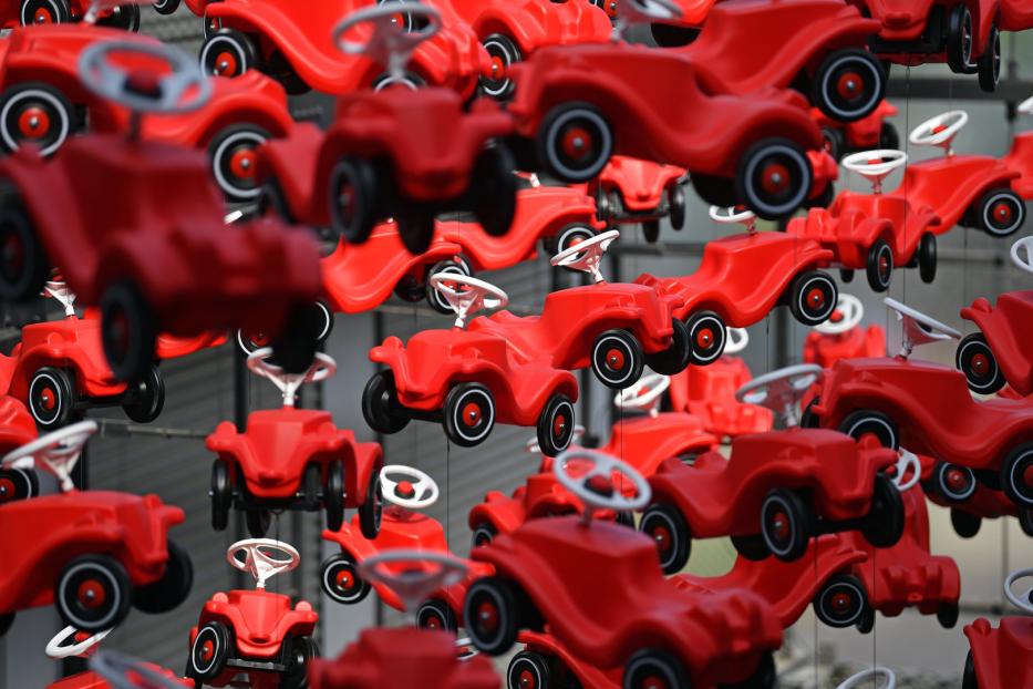 Viele rote Bobby-Cars hängen in der Luft.