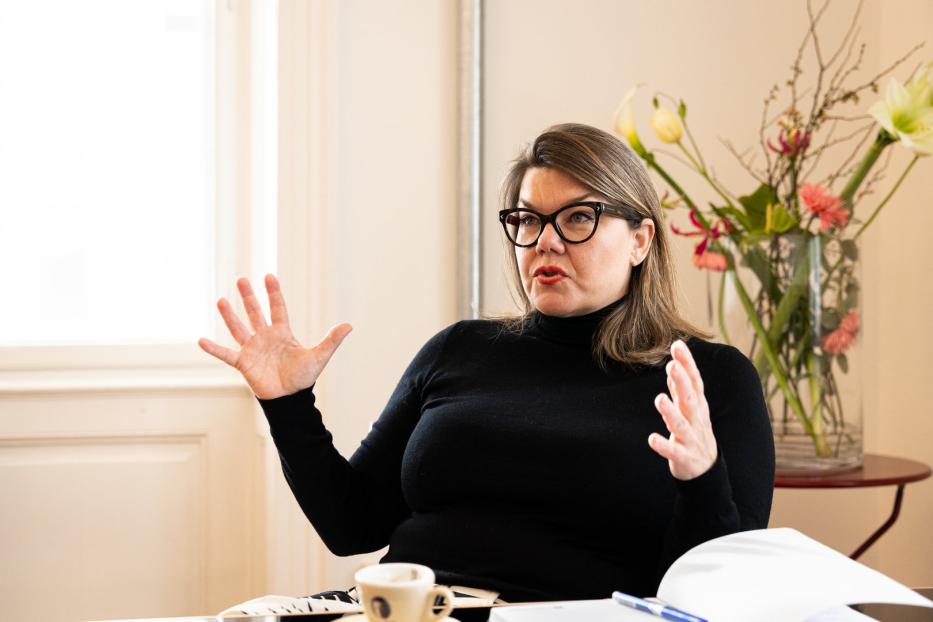 Eine Frau mit Brille gestikuliert während eines Gesprächs.