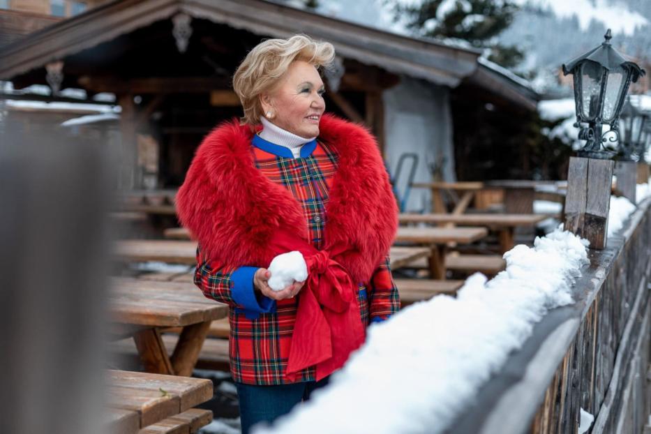 Eine Frau in Winterkleidung hält einen Schneeball in der Hand.