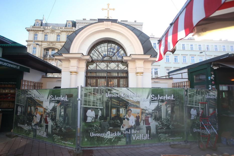 Ein Blick auf den Naschmarkt in Wien, teilweise durch einen Bauzaun verdeckt.