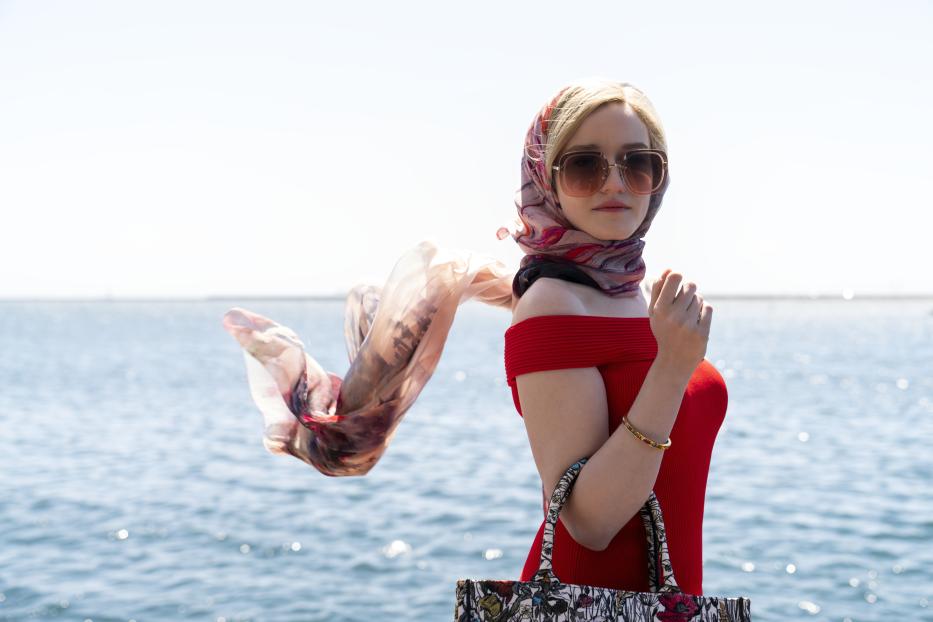 Eine Frau mit Sonnenbrille und Kopftuch vor dem Hintergrund des Meeres.