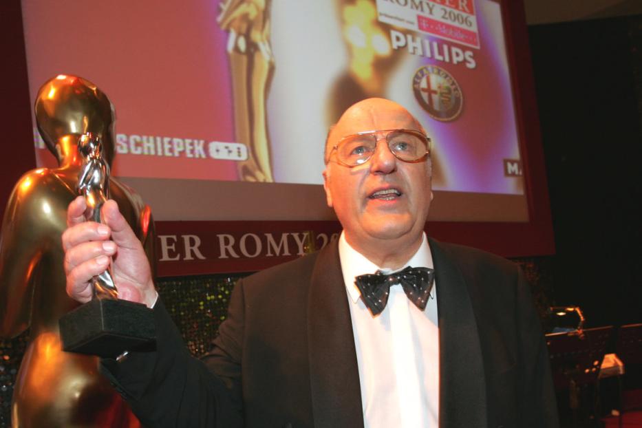 Ein Mann im Smoking hält eine Romy-Statue in der Hand.