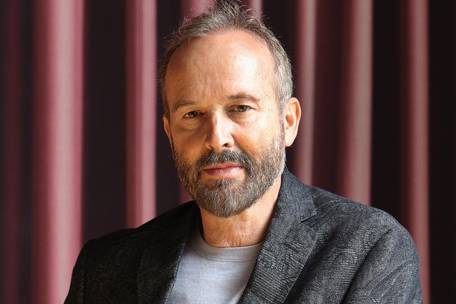 Ein Mann mit Bart lehnt an einem Geländer.