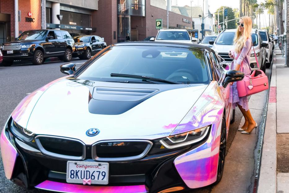 Paris Hilton steht neben ihrem auffälligen, farbwechselnden BMW i8.