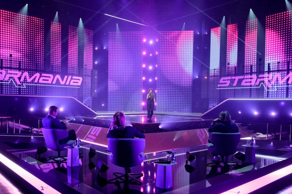 Eine Sängerin steht auf der Bühne von „Starmania“ vor drei Juroren.