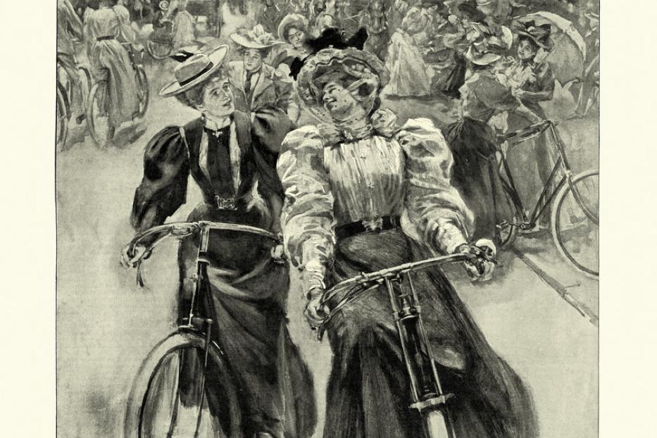 Zwei elegant gekleidete Frauen fahren im Battersea Park Fahrrad.
