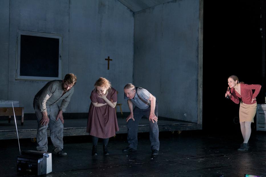 Szene aus einem Theaterstück mit vier Schauspielern auf einer Bühne.