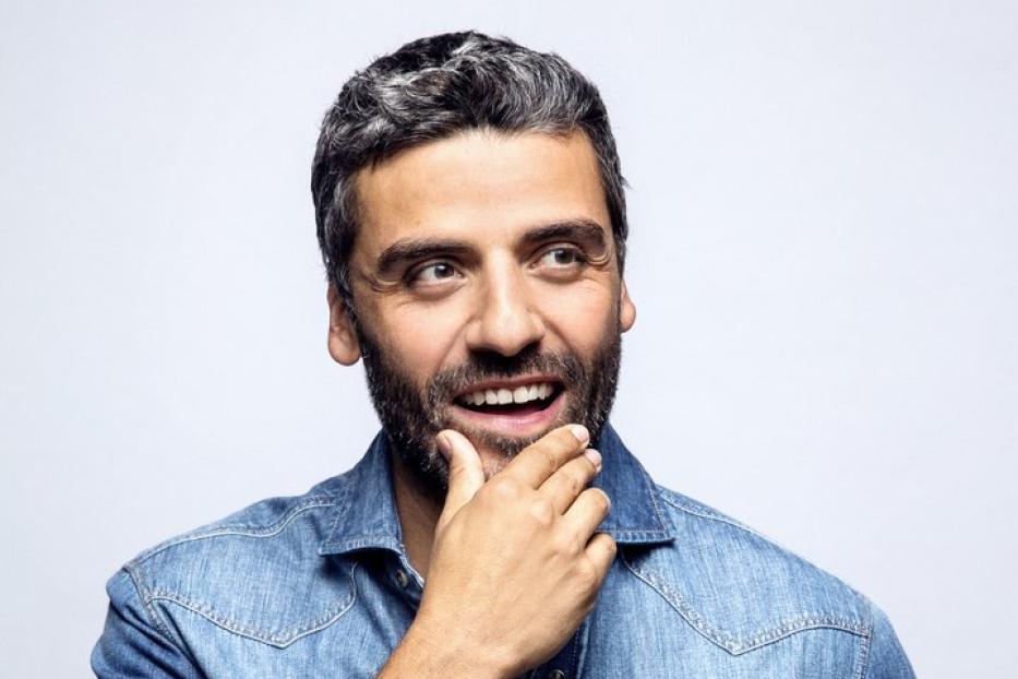 Oscar Isaac lächelt und blickt nachdenklich zur Seite.